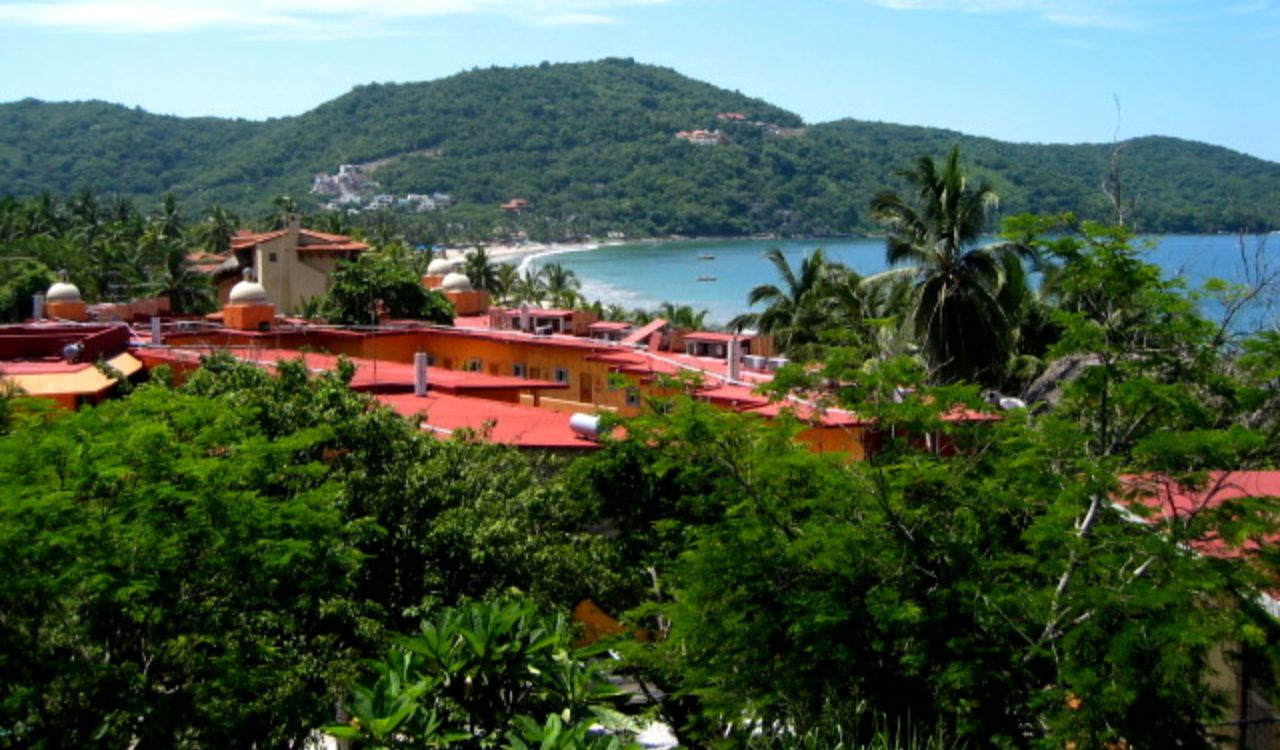 Zihuatanejo, Mexico — Colorful rooftops nestled among lush greenery overlooking a peaceful bay and forested hills