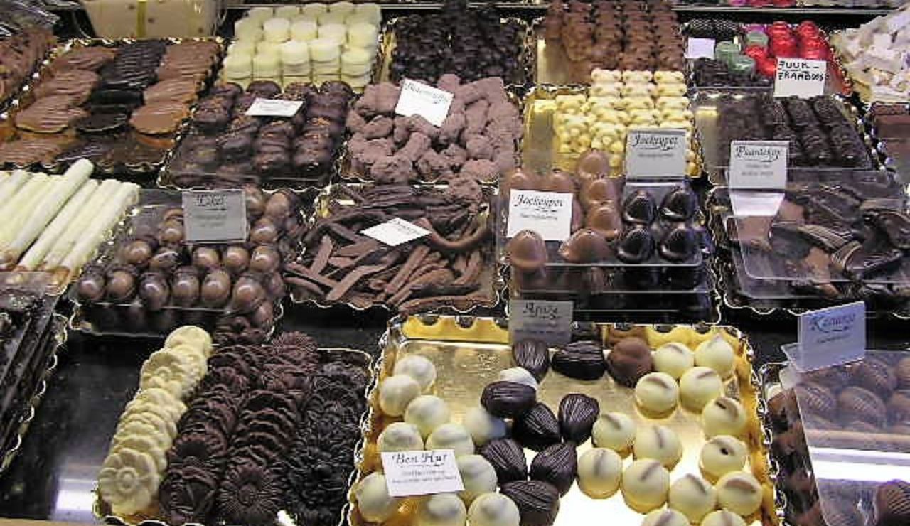 Display case filled with a wide variety of Belgian chocolates and truffles, including dark, milk, and white chocolate selections.