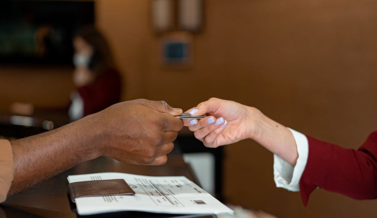 Hotel receptionist handing a key card to a guest at the front desk.
