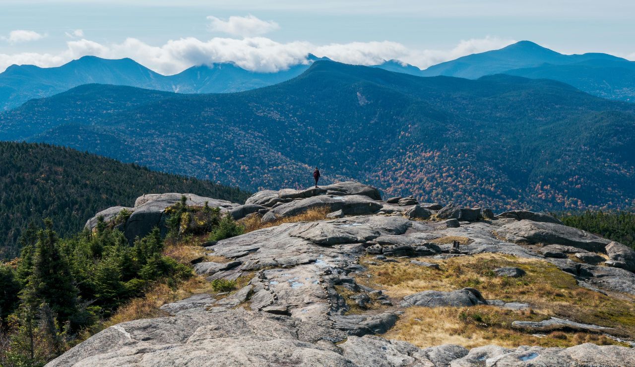 a rocky Adirondack summit with misty valleys below.