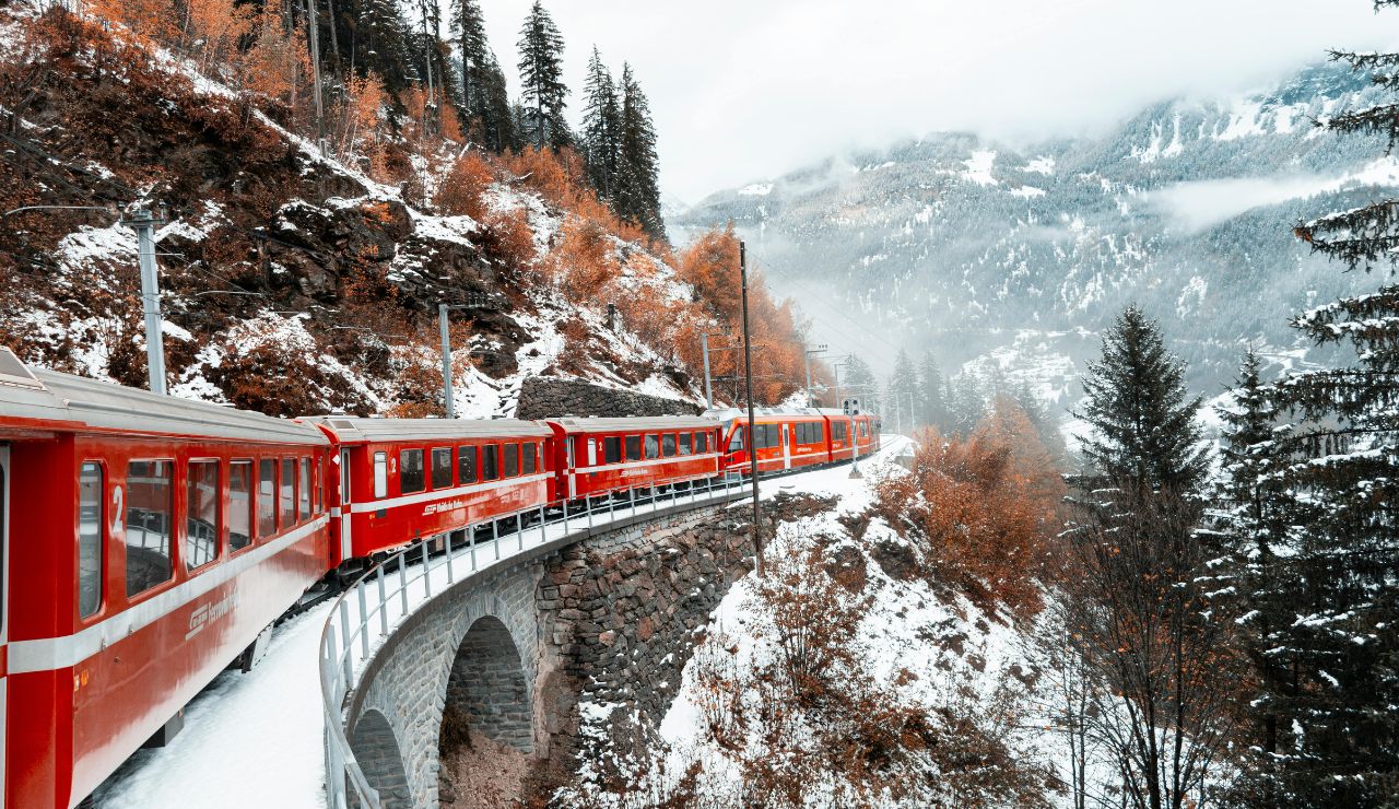A train passing through the Swiss Alps with snow-covered peaks and valleys.