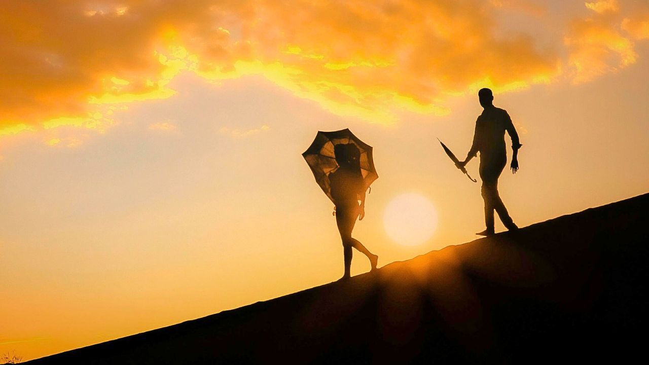 Couple walking among ancient ruins during golden hour with sunset sky