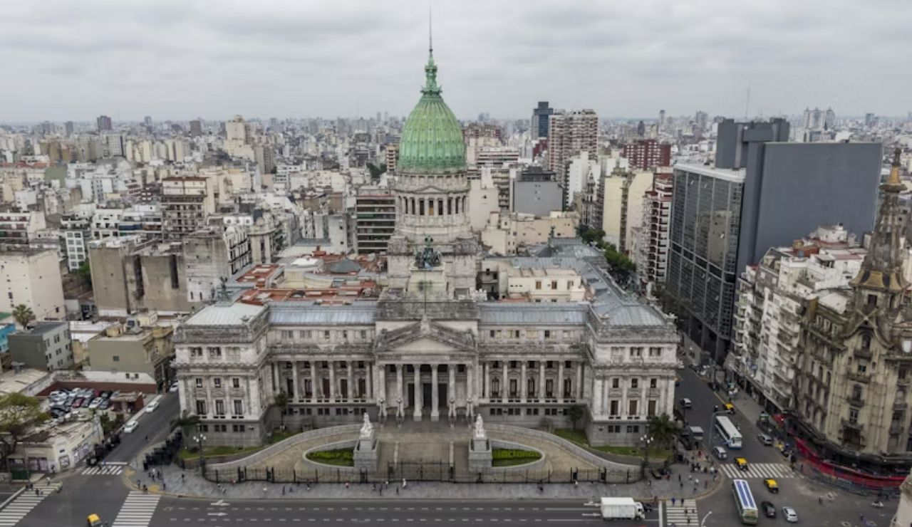 Aerial view of the Argentine National Congress building in Buenos Aires, surrounded by the city's skyline under a cloudy sky.