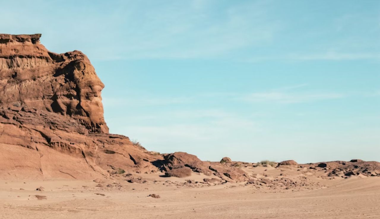 Rocky desert landscape with sandstone formations under a clear blue sky.