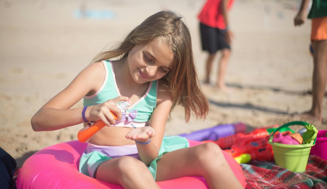 Sunscreen bottle and sunhat on beach towel
