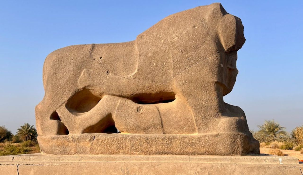 Ancient Lion of Babylon stone statue in Iraq, symbolizing strength and protection, set against a clear sky and natural surroundings.