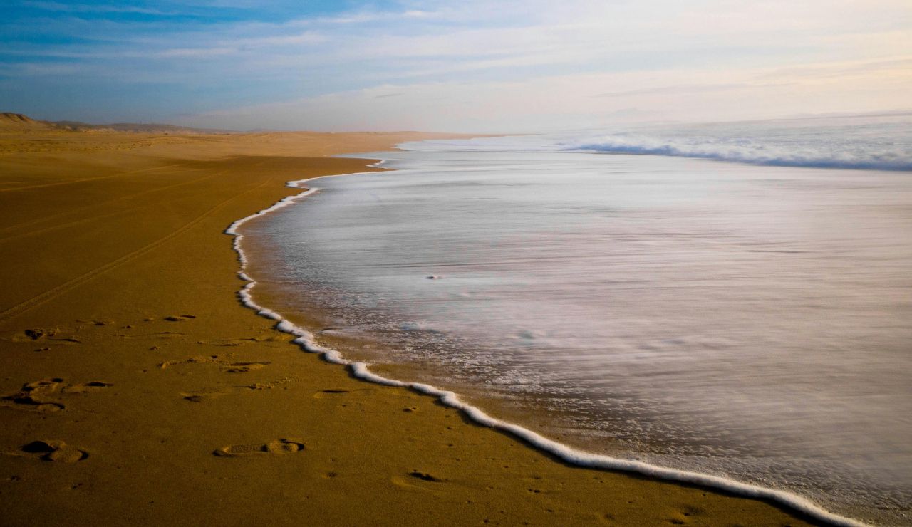 Wide, empty beach with golden sand and blue Atlantic waters.