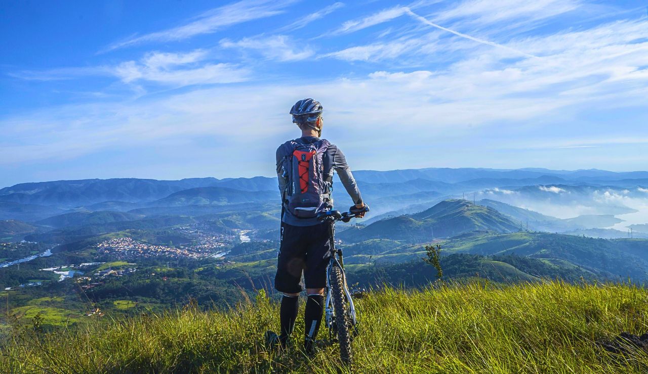 Cyclist cruising through open valley with forested hills in background