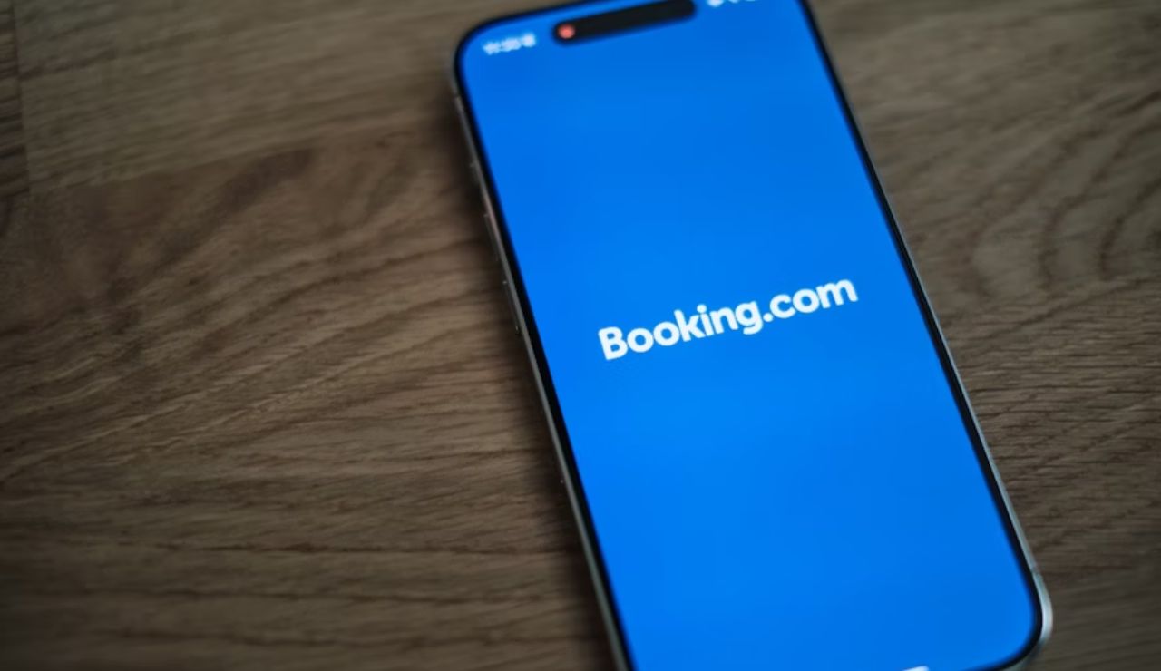 Smartphone displaying the Booking.com app loading screen on a wooden surface.