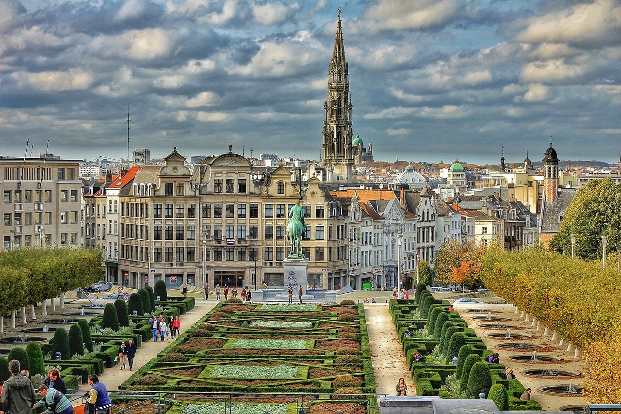 View of the Mont des Arts garden in Brussels with historic buildings and a tall church spire in the background.