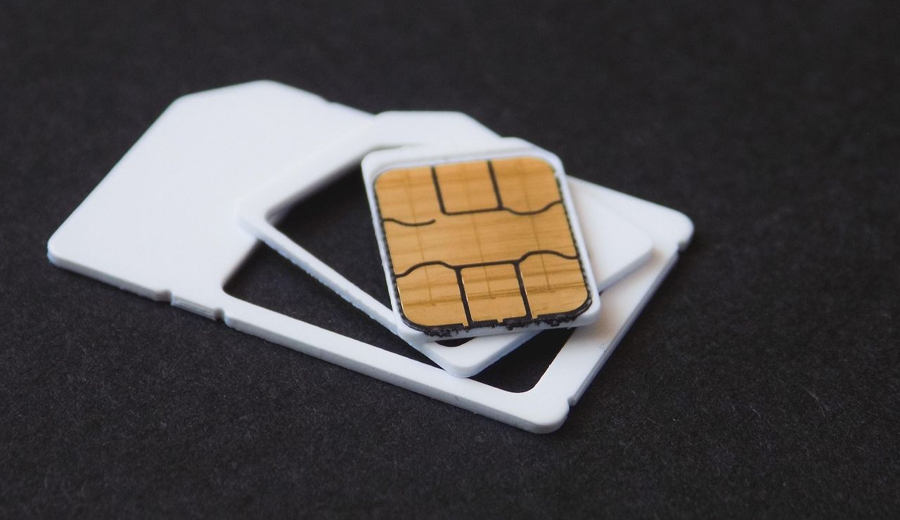 Close-up of a SIM card with plastic adapters placed on a black surface.