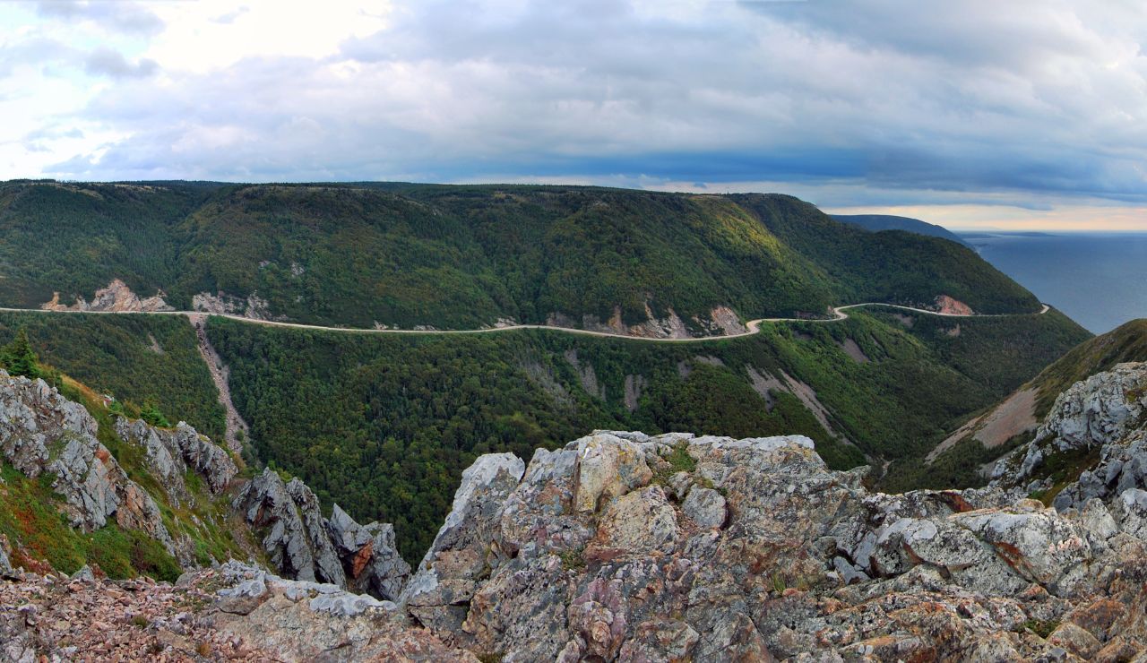 Scenic view of Cabot Trail winding through cliffs and forest along the Atlantic coast in Nova Scotia.