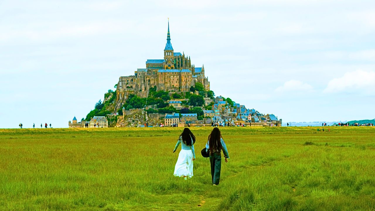 A romantic couple walking toward a European-style castle at sunset