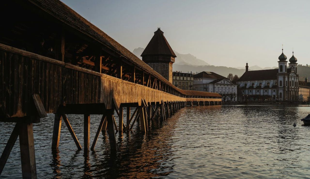 Chapel Bridge in Lucerne at sunset with Water Tower and church view.