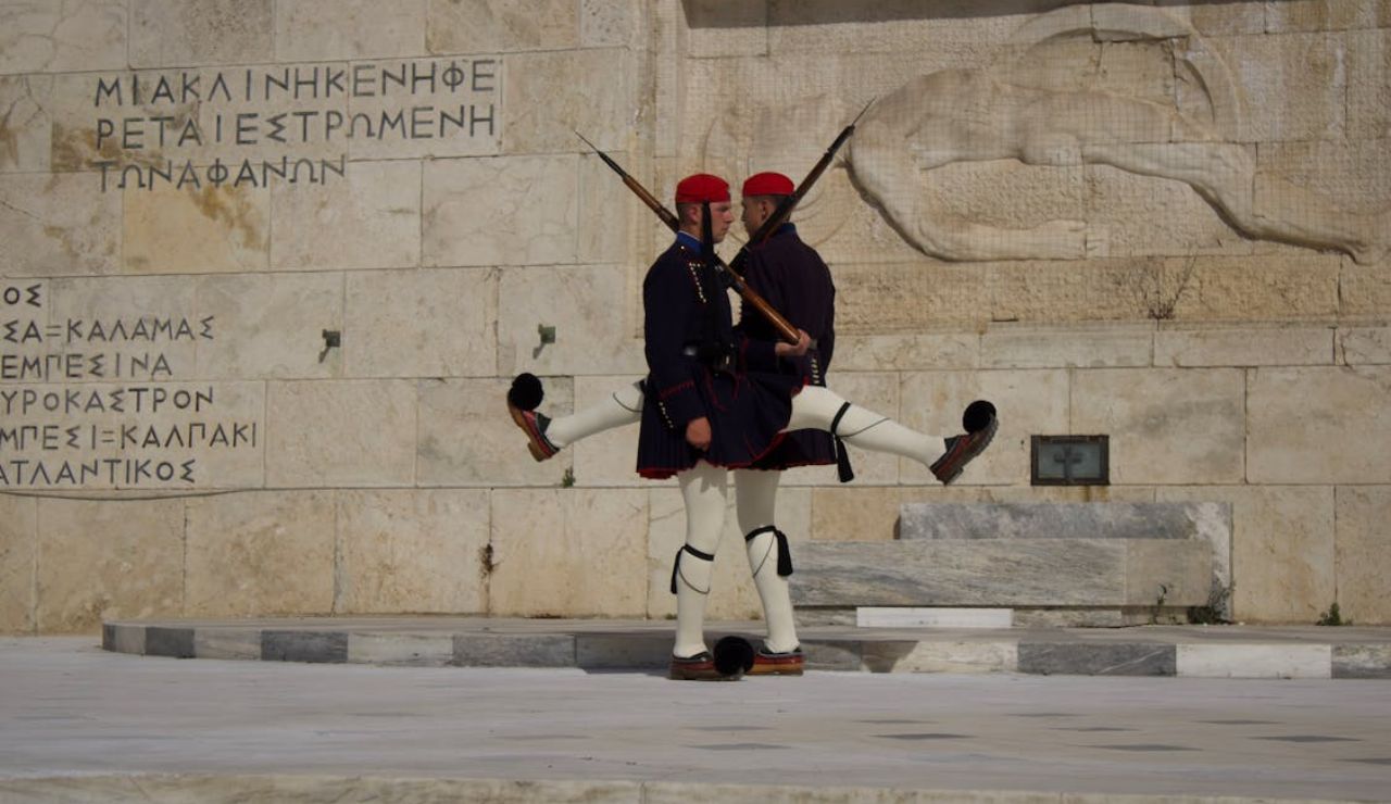Two Evzones guards performing a ceremonial march in traditional uniform at the Tomb of the Unknown Soldier in Athens, Greece.