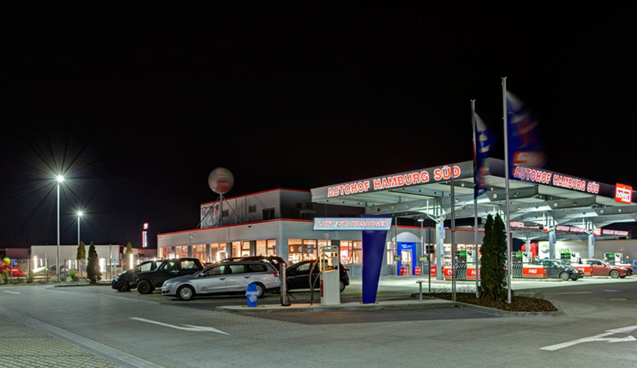 Well-lit highway service station and gas station at night, with parked cars and illuminated signage reading "Autohof Hamburg Süd."