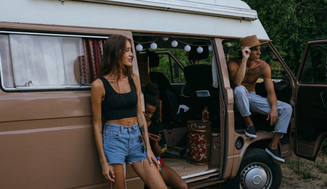 Three young adults relaxing around a vintage RV camper, highlighting the importance of choosing the right RV for comfort and lifestyle.