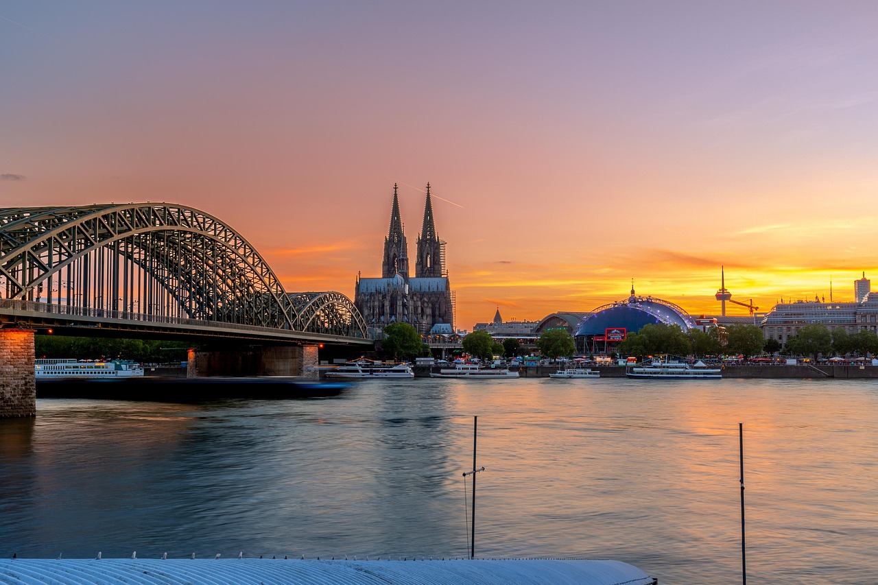 Sunset view of Cologne Cathedral and Hohenzollern Bridge over the Rhine River in Cologne, Germany.