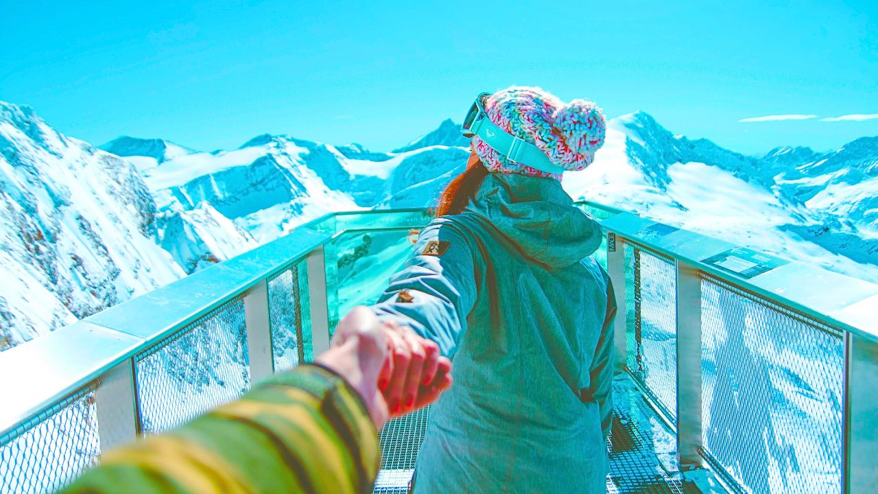 A couple on a scenic view at snowy Alpine mountains.