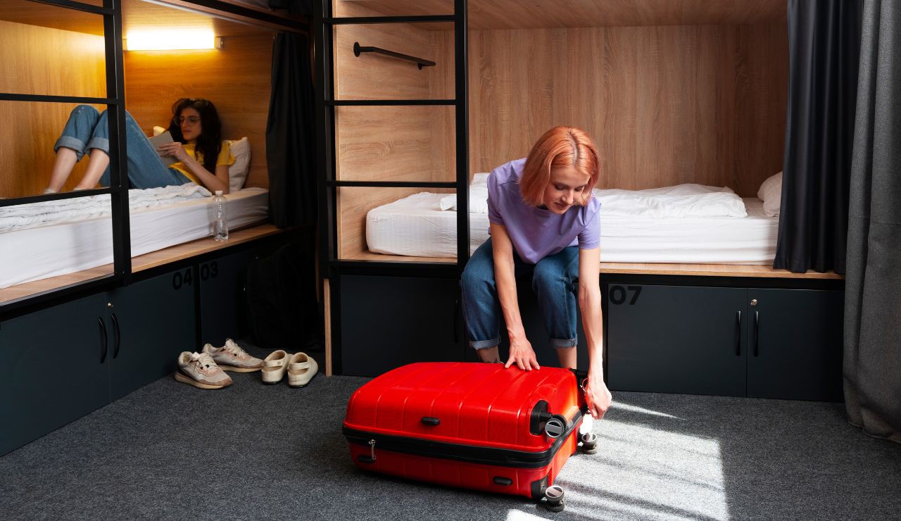 A cozy, modern hostel room with a couple placing bags near the bed.