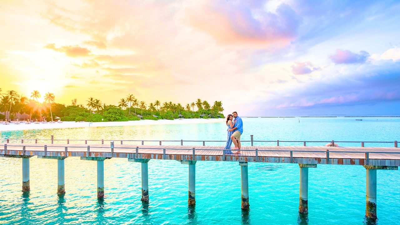 Couple sharing a romantic kiss on a bridge at sunset