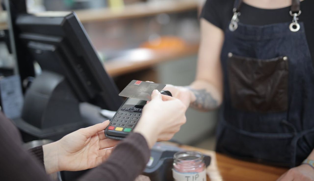 A person handing a credit card to a cashier at the register to complete a payment.