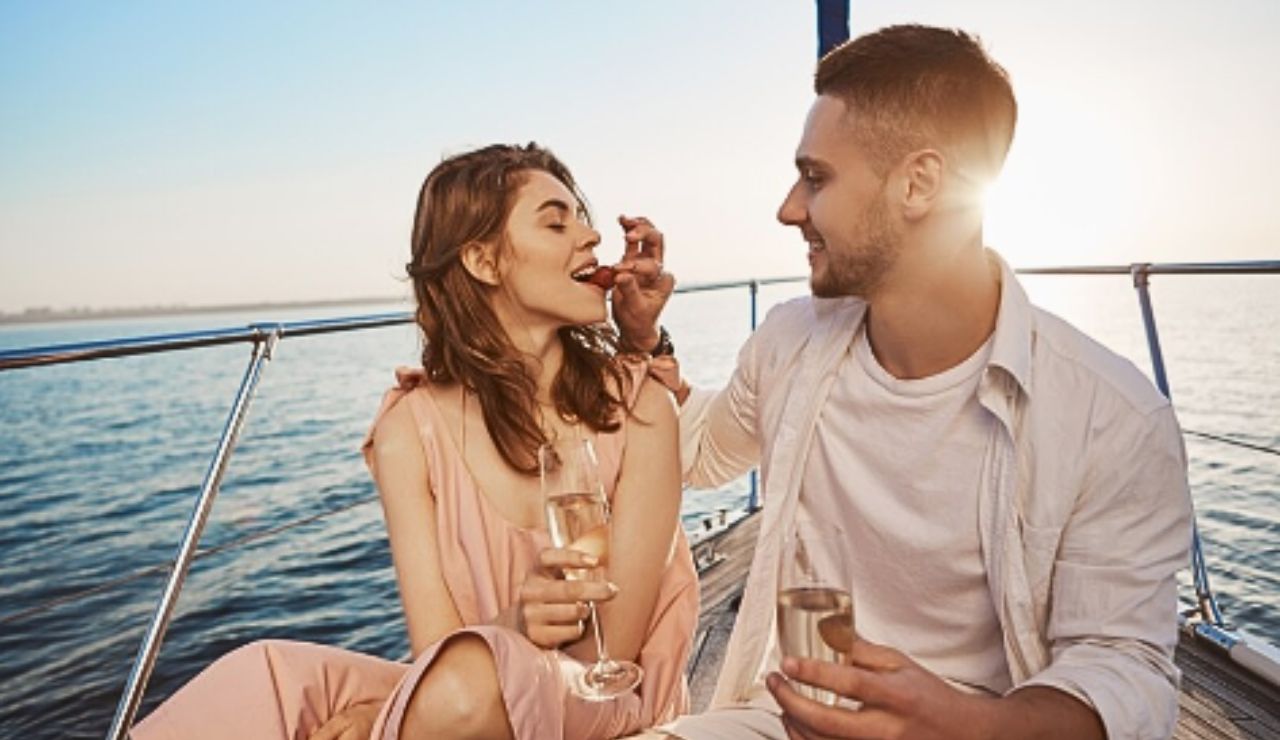 A couple toasting with champagne on a cruise ship balcony with sunset view.
