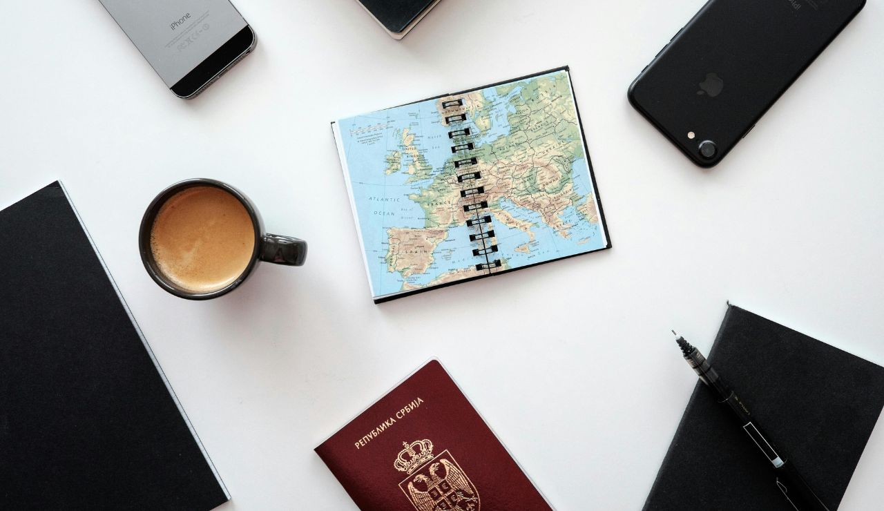 Open travel journal with handwritten itinerary and coffee beside a map