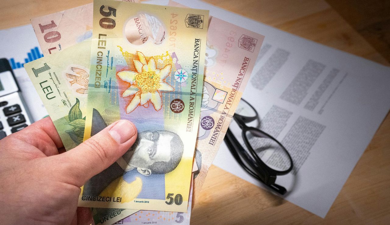 Traveler exchanging money at a bank with multiple currencies on the table