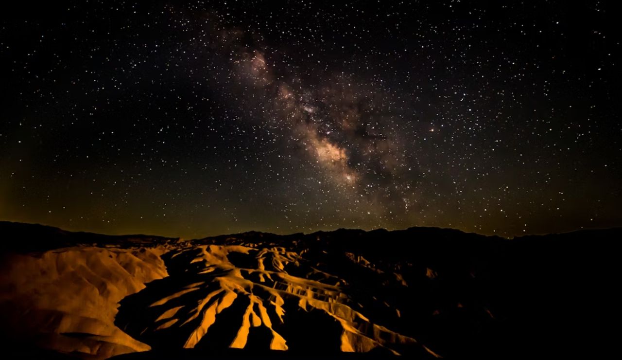 The Milky Way shines over glowing desert ridges in Death Valley National Park.