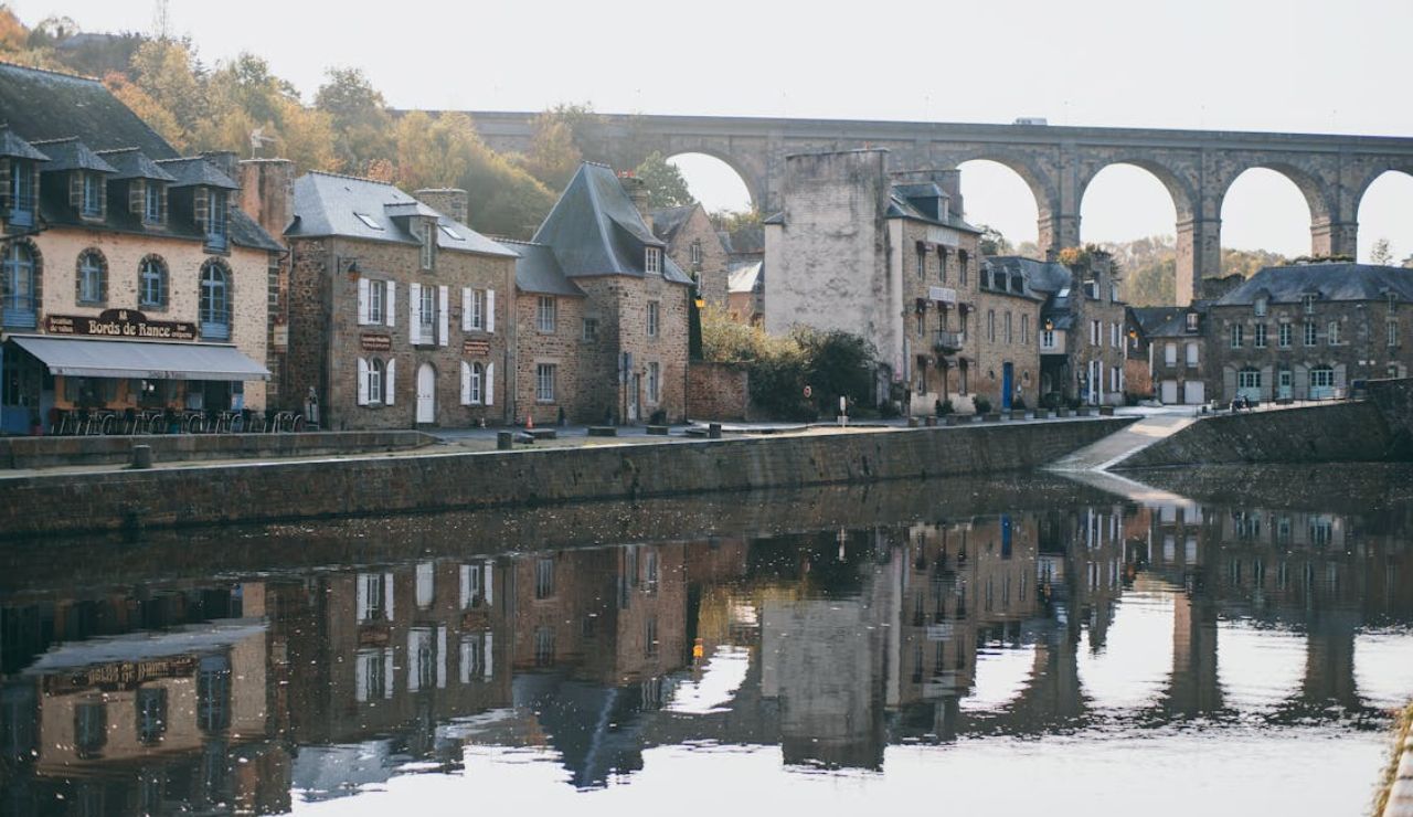This is Dinan, a medieval town in Brittany, France, known for its half-timbered houses, cobbled streets, and the scenic Rance River overlooked by a striking stone viaduct.