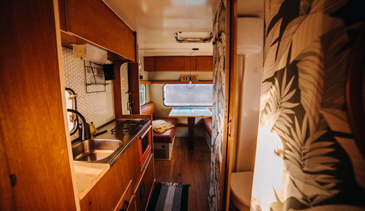 Interior of a cozy, downsized RV featuring a compact kitchen, dining area, and modern decor – perfect for minimalist living.