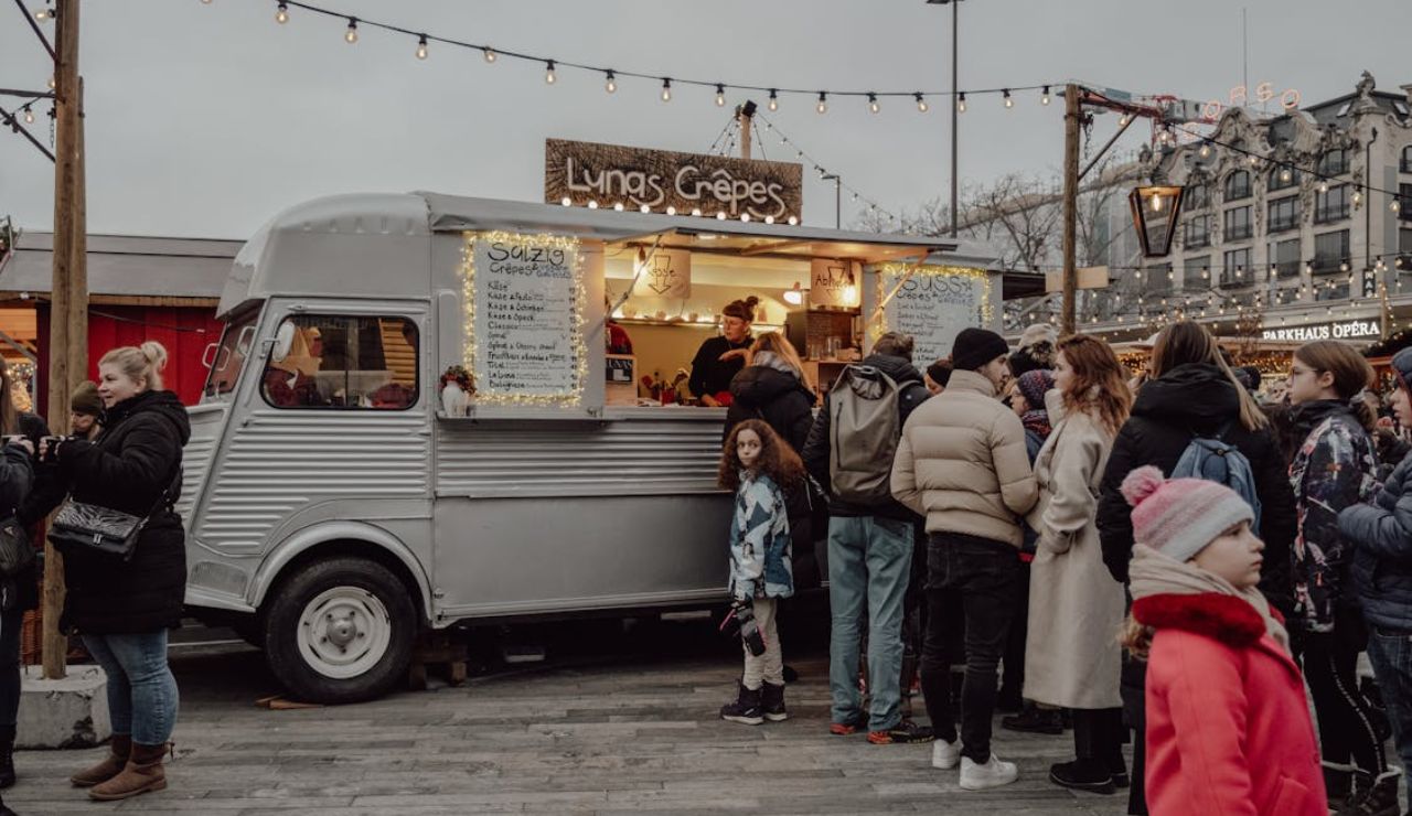 People standing in line at a food truck labeled "Lyngs Crêpes" at an outdoor market.