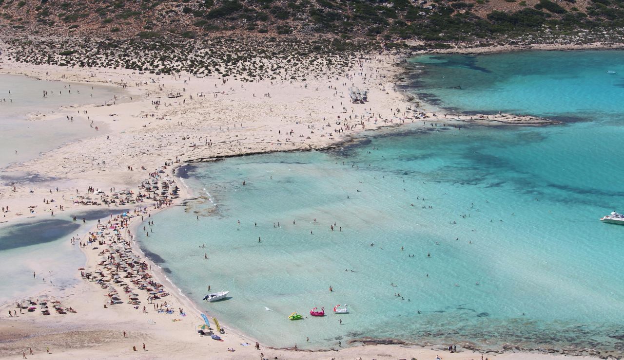 Pink-hued sand meeting clear shallow waters.