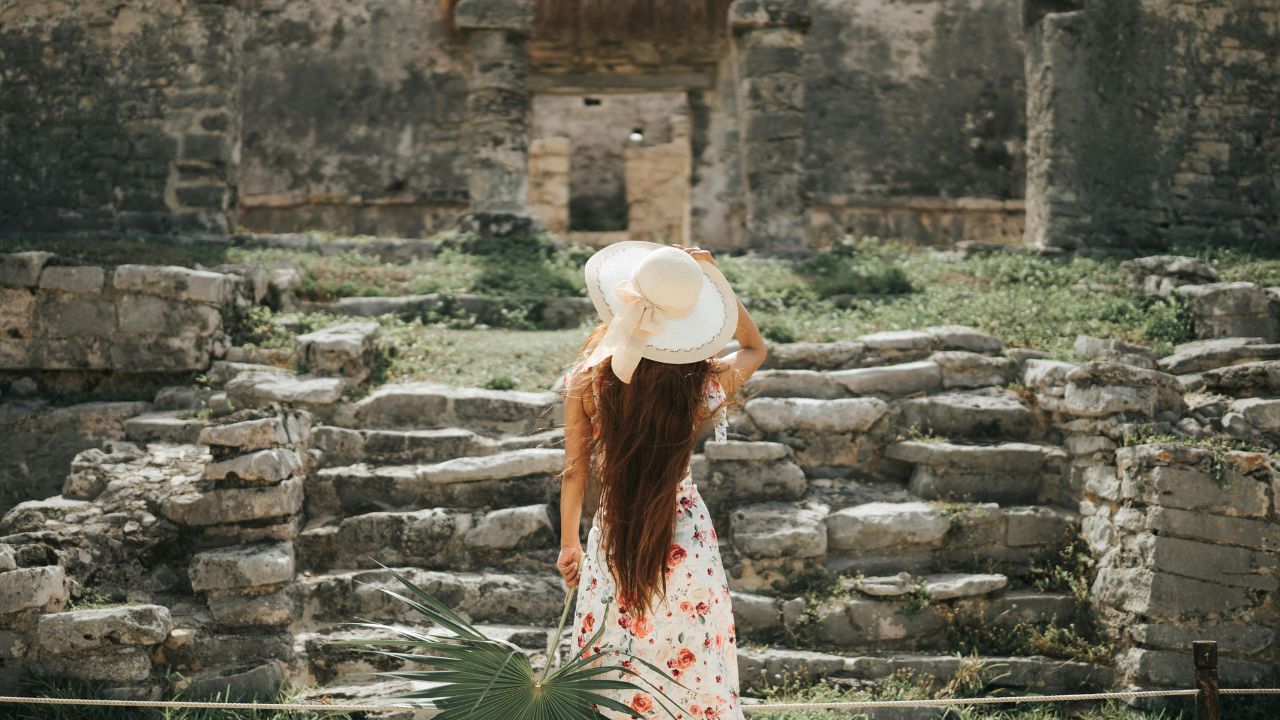 Back View o Woman in a Summer Outfit Looking at House of the Halach Uinic at Mayan Ruins in Tulum, Mexico