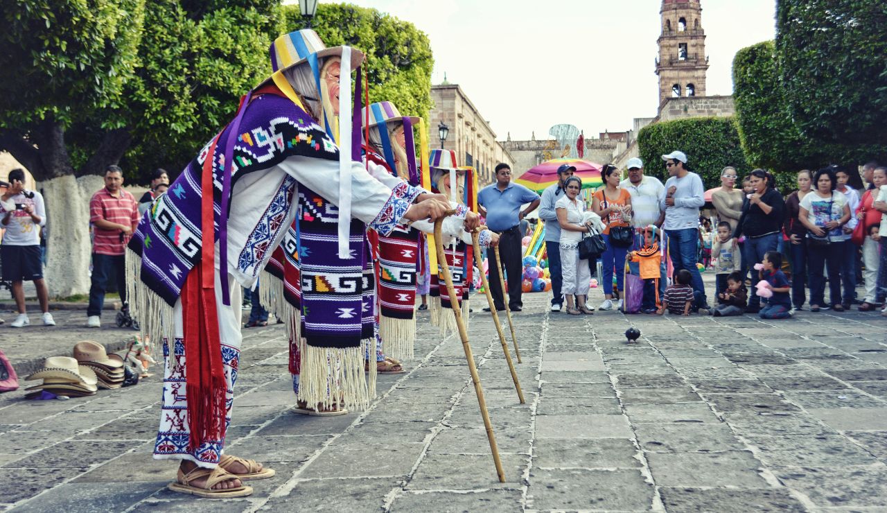 A person walking toward a street performer or small crowd in a lively square.