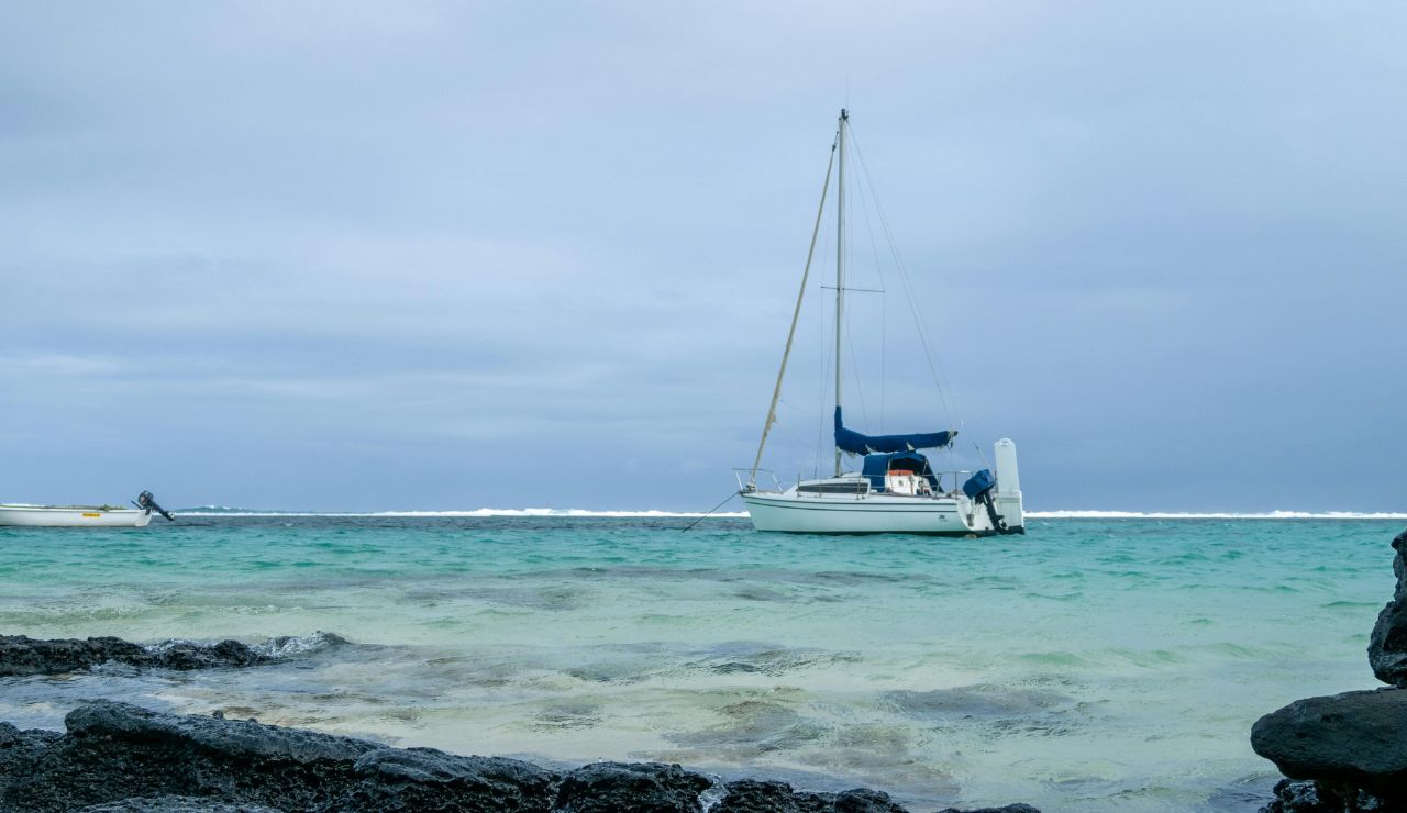 A small sailboat anchored near volcanic Galápagos islands in calm blue waters.