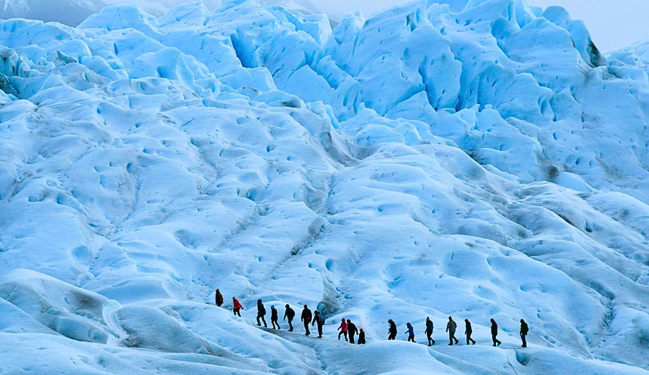 Hikers climbing rocky glacier terrain on the way to the ice caves