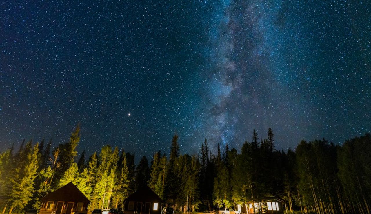 A clear night sky bursts with stars above cabins nestled near the Grand Canyon.
