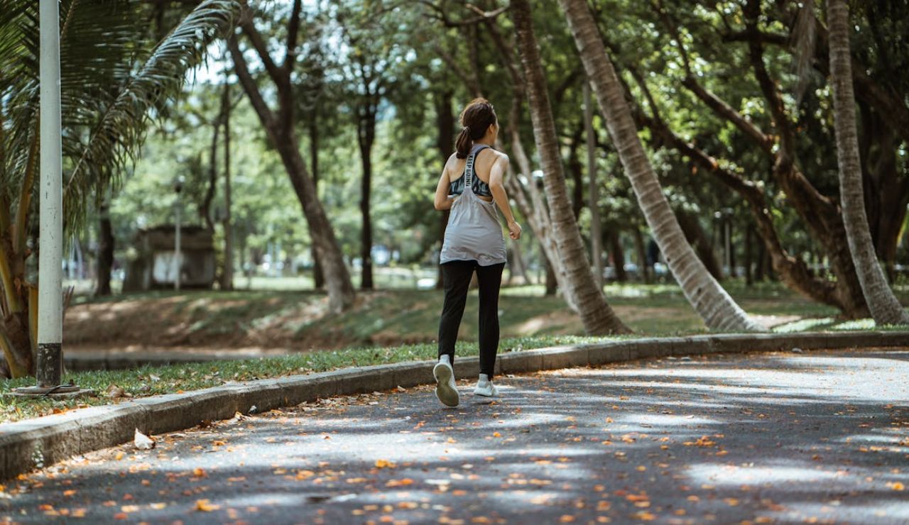 Woman jogging on a curved path in a park in Seattle, Washington, surrounded by tall trees and greenery.