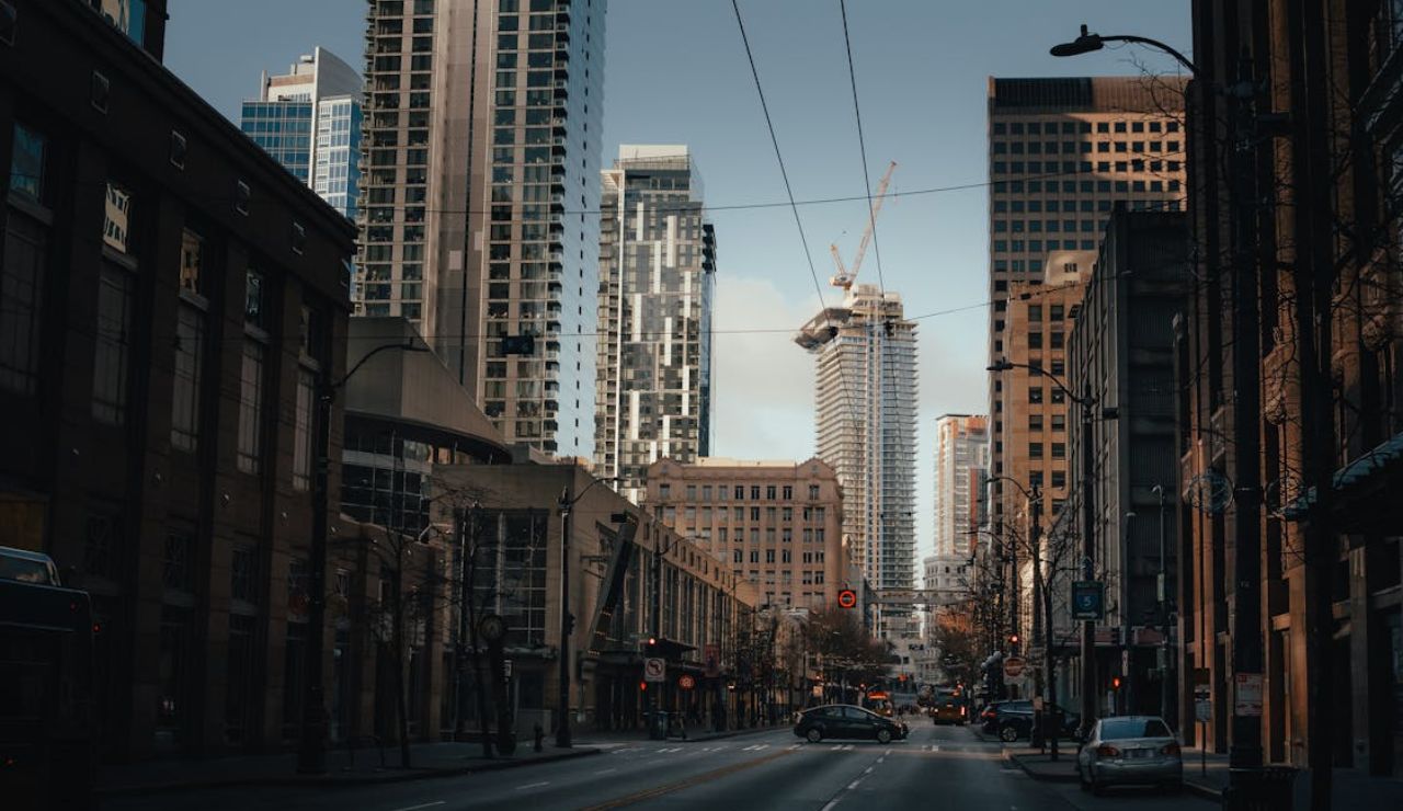 Downtown city street lined with tall buildings, symbolizing the rising cost of living in urban areas.
