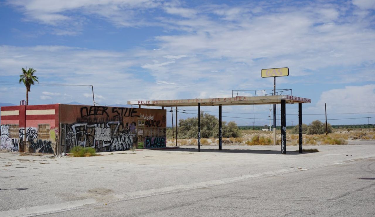 Abandoned and graffiti-covered gas station in a desert landscape.
