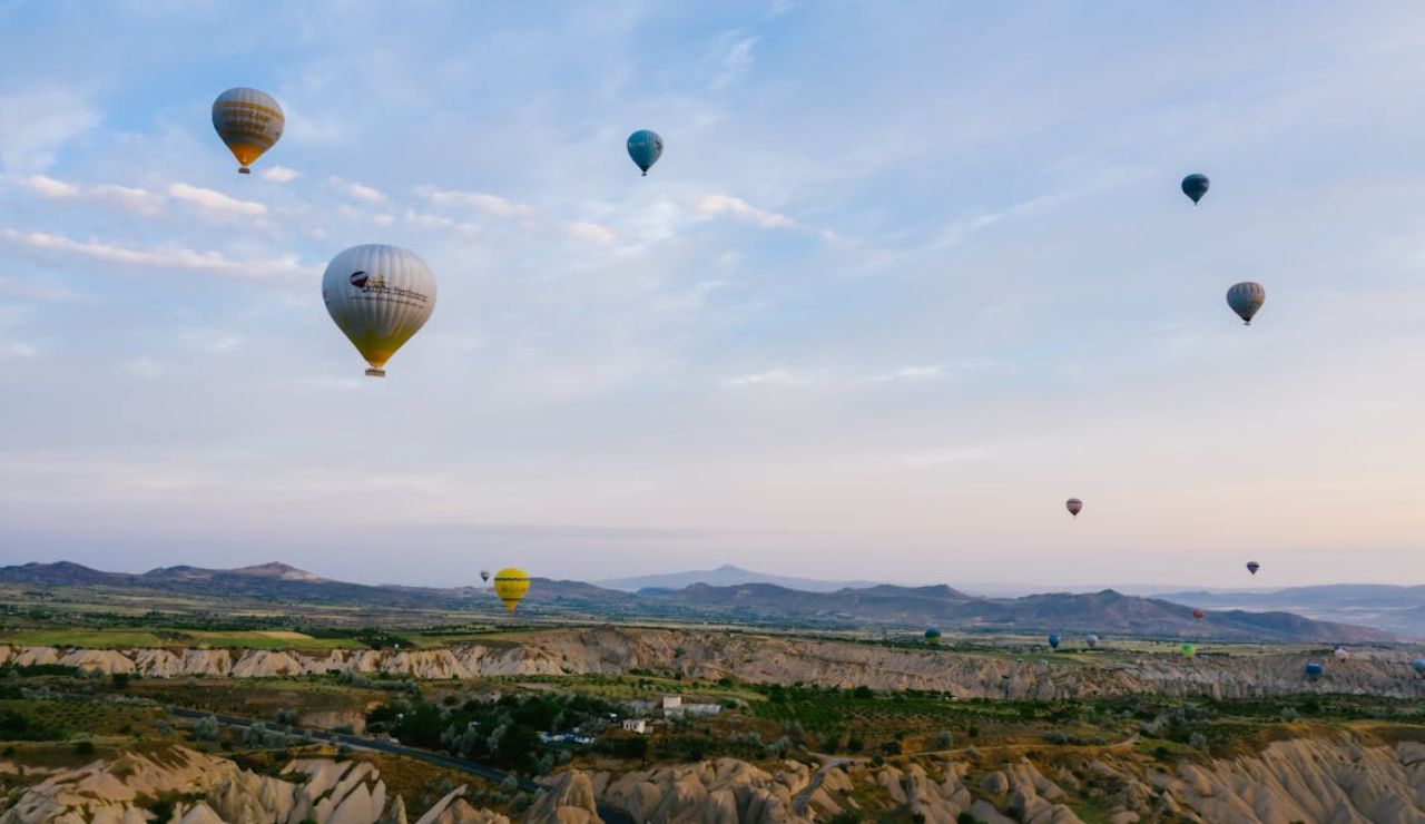 Hot air balloons floating over the rocky valleys of Cappadocia at sunrise.