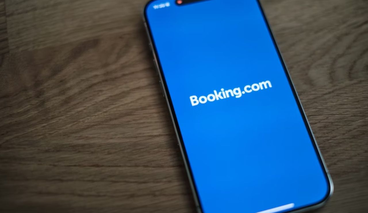 A smartphone on a wooden surface displaying the Booking.com app loading screen.