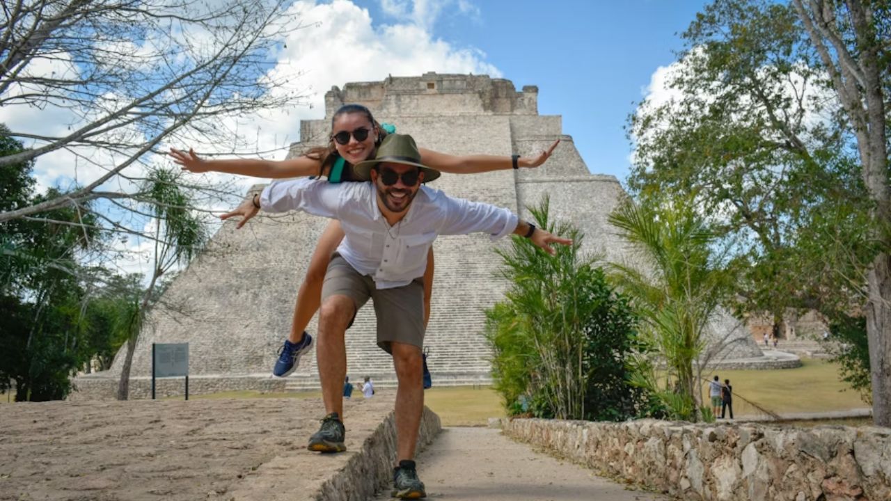 Couple playfully posing in front of an ancient Mayan pyramid at Uxmal, Mexico.