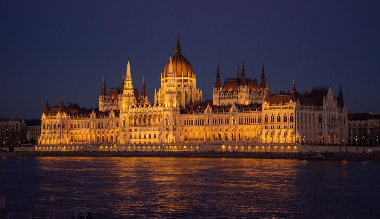 The Hungarian Parliament Building in Budapest illuminated at night, reflecting on the waters of the Danube River.