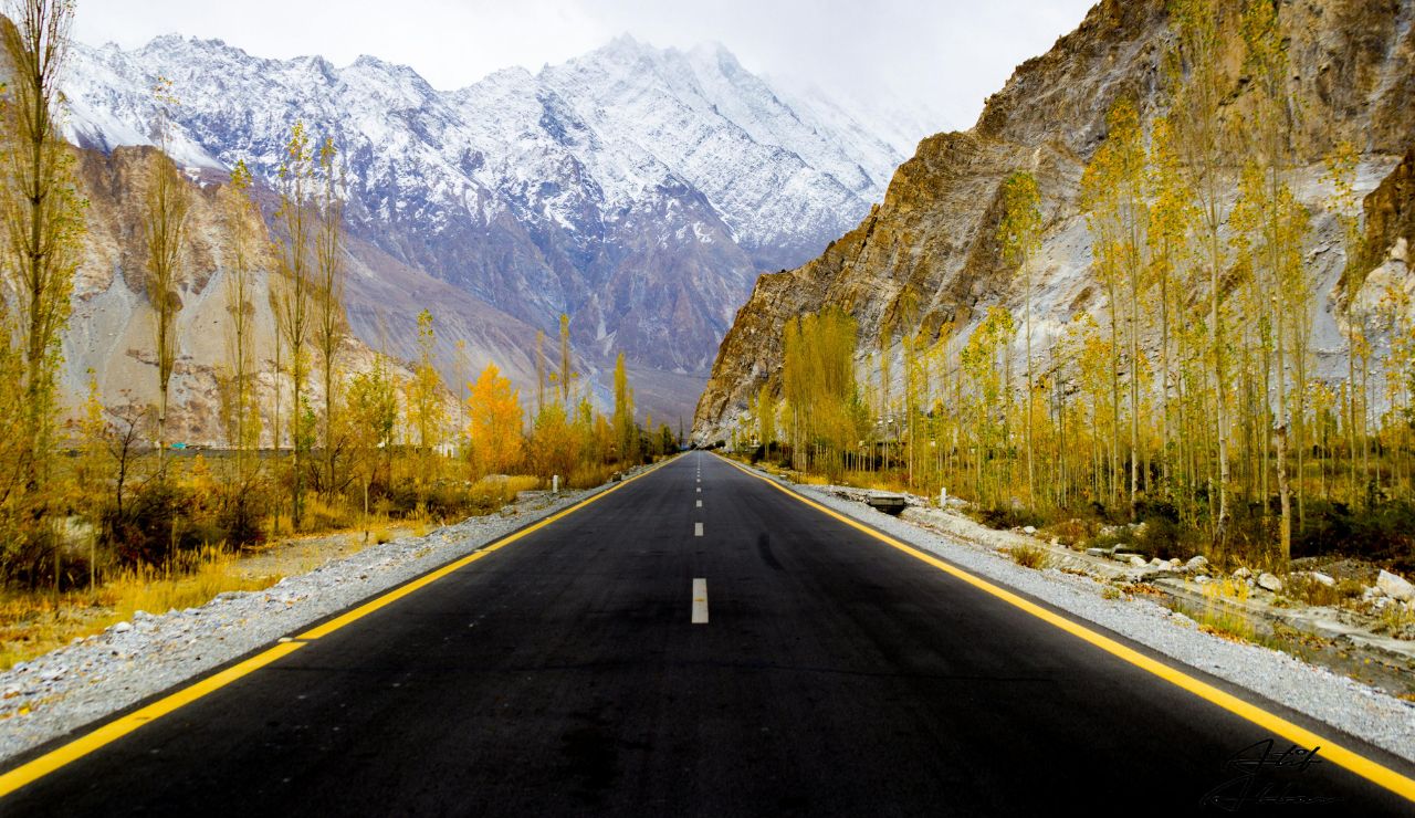 Hunza Valley road with snowcapped peaks and apricot trees