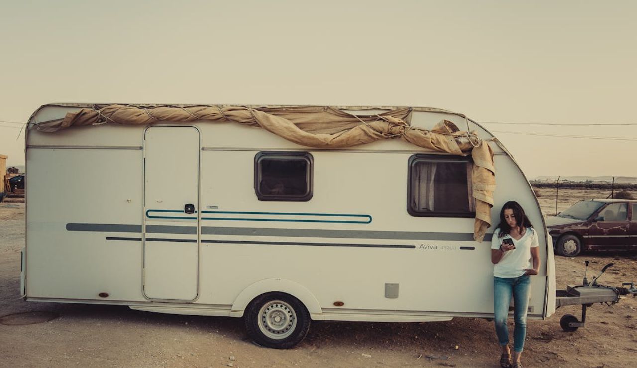 Woman by trailer checking phone, showing spotty internet on the road.