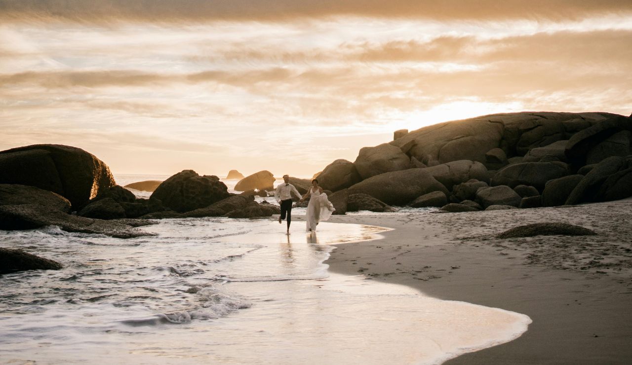 Couple walking hand-in-hand along Jensen Beach during sunrise.
