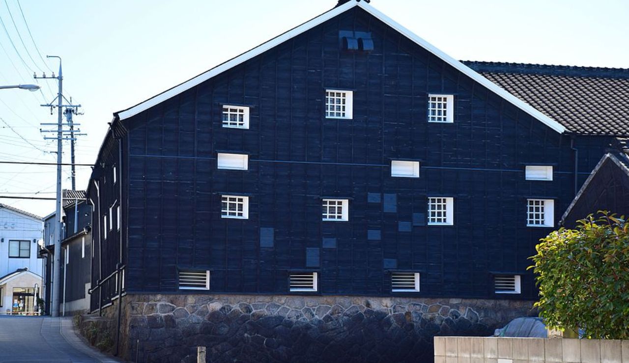Traditional Japanese building with a distinctive black wooden exterior and small square windows.